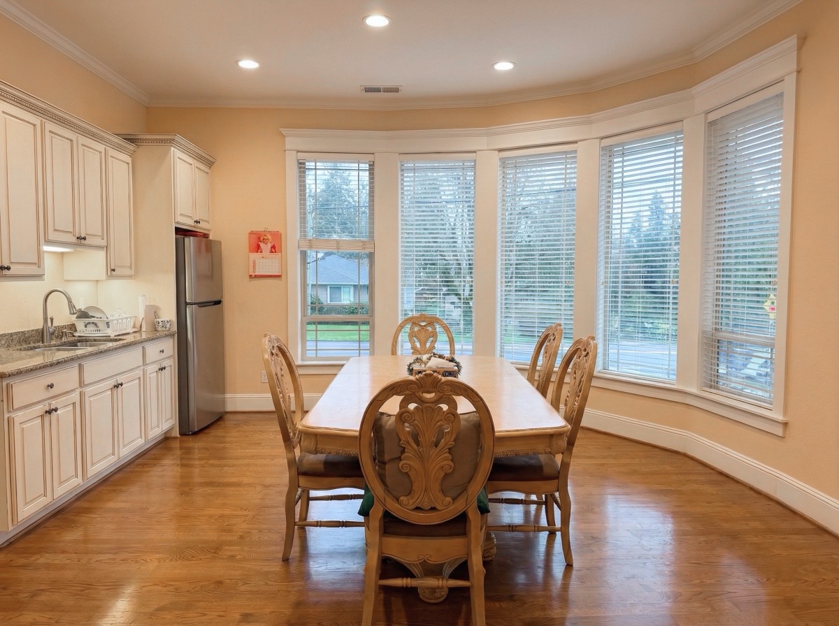 Elegant dining room with bay windows, wooden dining table and ornate chairs, connected to kitchen